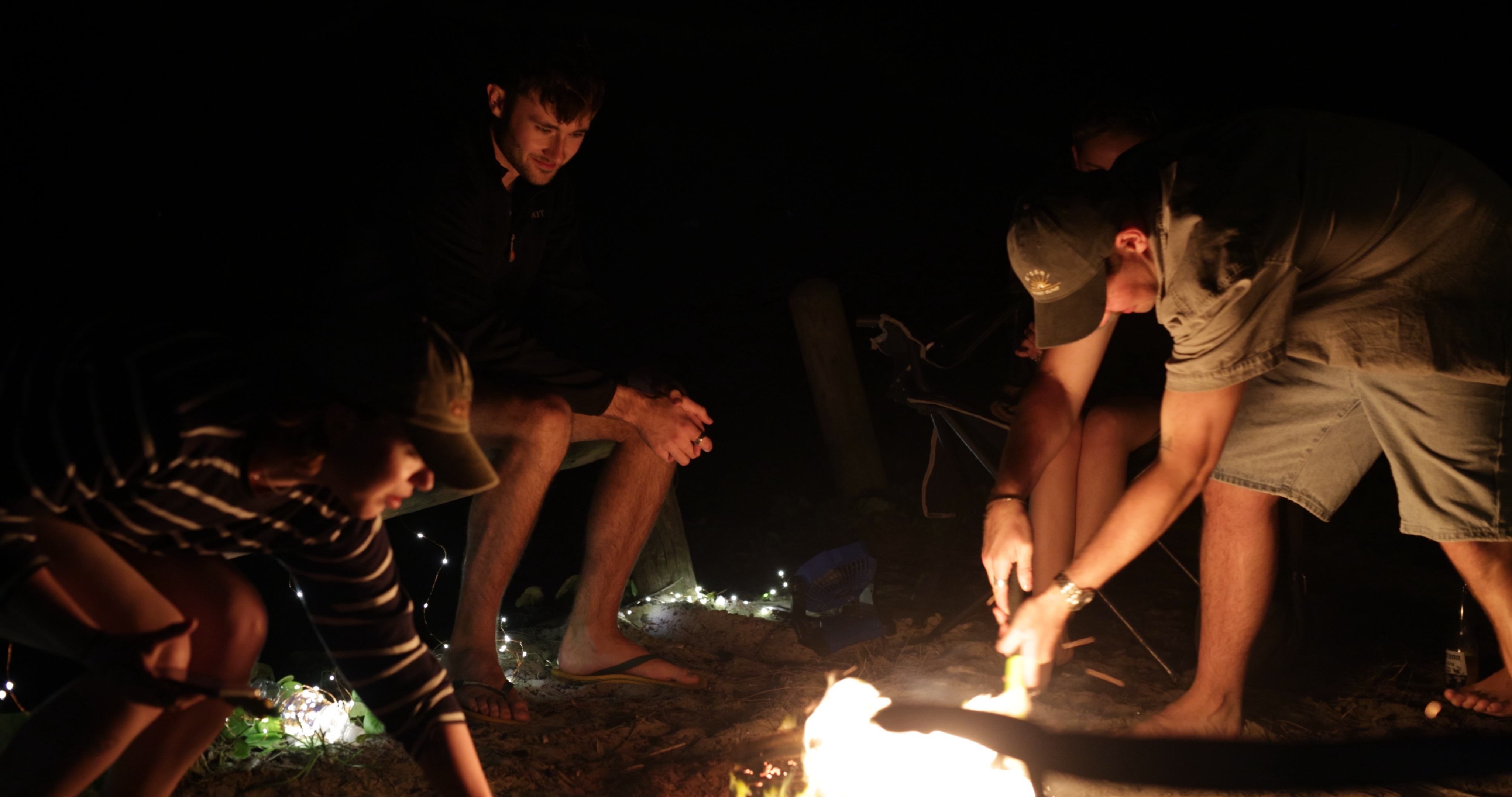 Two 4WD vehicles set up with awnings on a wide open bush camp with rugged tracks and a group of travellers celebrating
